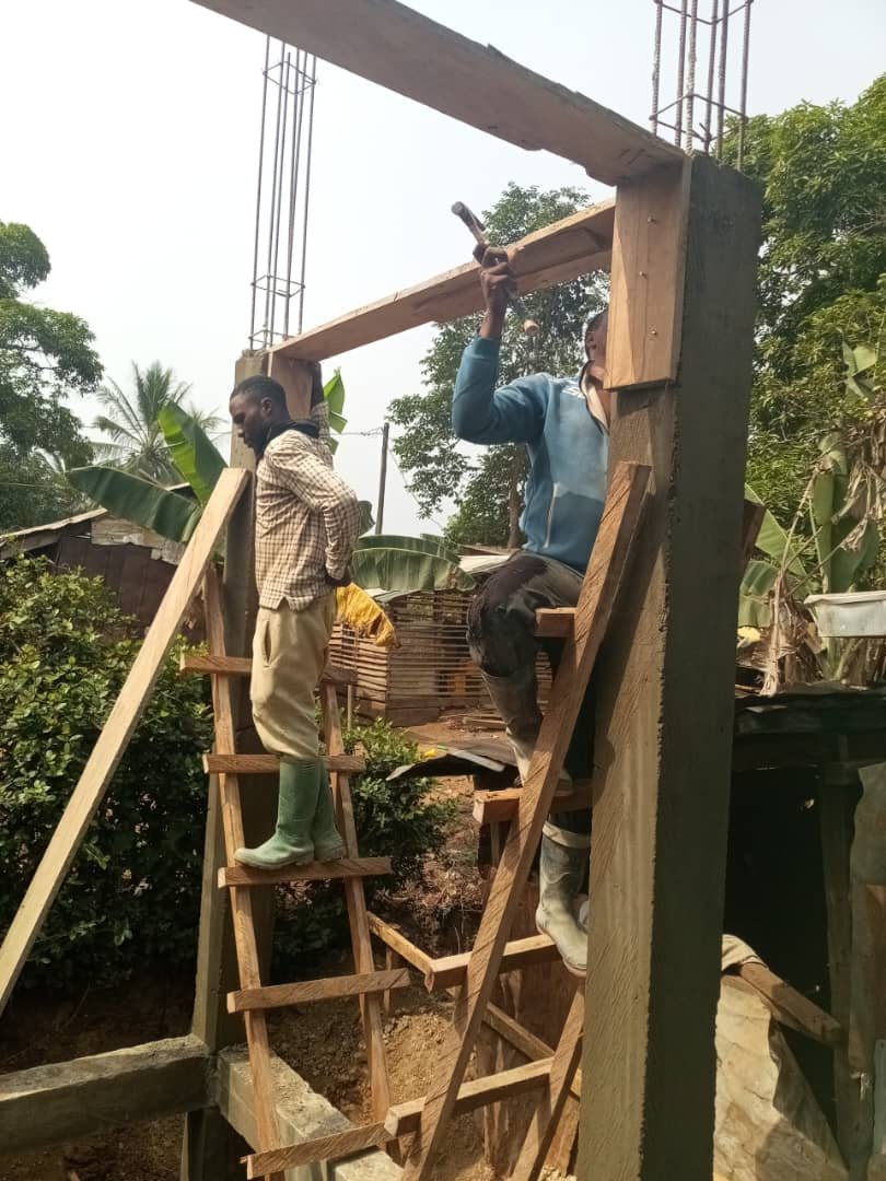 Two workers building the water tower framework at Rainbow Orphanage
